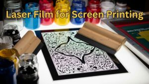 Close-up of a laser film sheet with bold black design on a lightbox, surrounded by screen printing tools